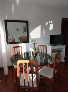 una sala da pranzo con tavolo in vetro e sedie di Apartamento Santa Marta a Santiago de Compostela