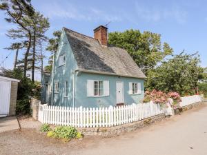 una casa azul con una valla blanca en Dinam Lodge, en Gaerwen