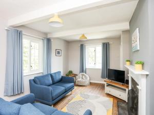 ein Wohnzimmer mit einem blauen Sofa und einem TV in der Unterkunft Dinam Lodge in Gaerwen