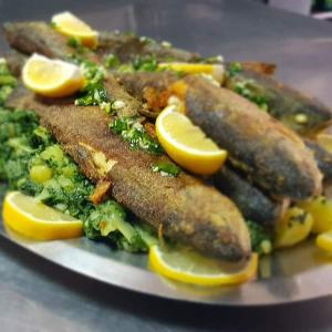 a plate of food with fish and broccoli and lemon slices at Hotel No-1 in Međugorje