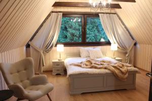 a bedroom with a bed and a window and a chair at Na Jeżynowej Polanie z gorącą balia in Wetlina