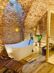 Cette chambre dispose d'une baignoire et d'un mur en briques. dans l'établissement LUXURY, PRIVATE WELLNESS IN PRADO MUSEUM NEW AUG21, à Madrid
