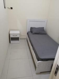 una piccola camera bianca con letto e comodino di Low-Priced Budget Rooms for rent near Dubai DAFZA a Dubai