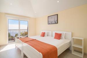 a bedroom with a white bed with a large window at OurMadeira - SeaView Apartment, countryside in Calheta
