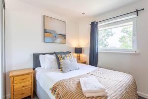a bedroom with a large bed and a window at Modern 2 bed BroomPark/Central apt. with Parking in Glasgow