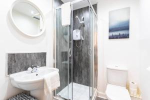 y baño con aseo, lavabo y ducha. en Modern 2 bed BroomPark/Central apt. with Parking, en Glasgow