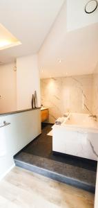 een grote badkamer met een bad en een wastafel bij Villa les érables Restaurant Linea in Spa