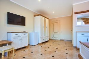 a kitchen with white cabinets and a tv on the wall at Guest house Nikolaevsky in Bilhorod-Dnistrovskyi
