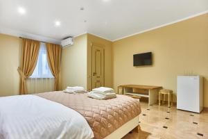 a bedroom with a bed and a desk and a television at Guest house Nikolaevsky in Bilhorod-Dnistrovskyi