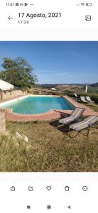 una foto de una piscina con 2 sillas de césped en Antonella House -Podere della Collina, en Palaia