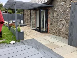 a patio with a stone house with a glass door at The Old Stables in Swansea
