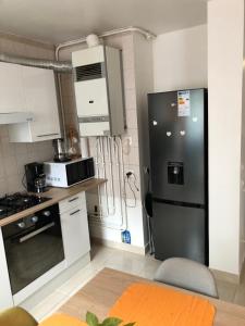 a kitchen with a black refrigerator and white cabinets at T3 Centre Ville Neuve in Tarbes