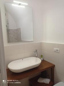 bagno con lavandino bianco e specchio di Santa Maria in Platea - Apartment a Montescaglioso
