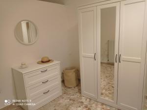una camera da letto con armadietto bianco e specchio di Santa Maria in Platea - Apartment a Montescaglioso