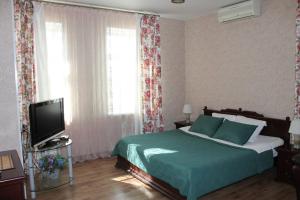 1 dormitorio con 1 cama y TV en Mini-Hotel Razgulyay, en Riazán