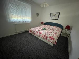 バラトンギュルクにあるFrankie Holiday Apartment III.のベッドルーム1室(赤い花の毛布付きのベッド1台付)