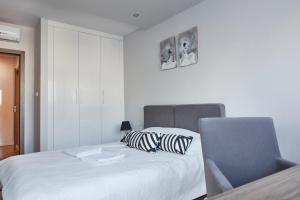 a white bedroom with a bed and a chair at Wronia Business Residence by BookingHost in Warsaw