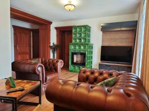 a living room with two leather couches and a fireplace at Penzion Lucs in Heľpa