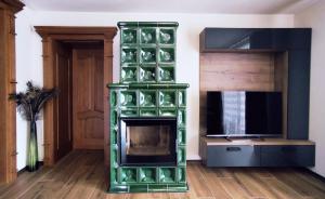 a green fireplace in a living room with a tv at Penzion Lucs in Heľpa