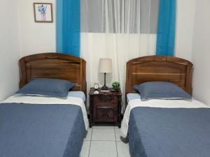 2 letti in una camera da letto con pareti bianche e blu di Entire Comfy apartment for you, 5 min SJO Airport a Alajuela