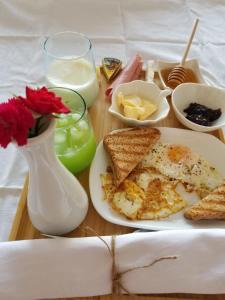une table avec une assiette d'œufs et de pain grillé et un vase dans l'établissement Home Away From Home, à Saranda
