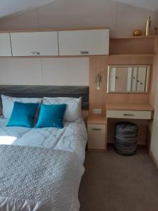 a bedroom with a bed with blue pillows and a mirror at RICK'S RETREAT static caravan near the beach with free wifi in Lossiemouth