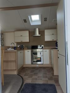 a kitchen with white cabinets and a stove at RICK'S RETREAT static caravan near the beach with free wifi in Lossiemouth