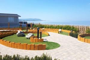 a garden with rocks on a patio with the ocean in the background at Hoburne Devon Bay Static 3 Bed in Goodrington