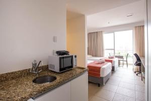 um quarto de hotel com um lavatório e um quarto em Flat 905 - Localização privilegiada em Macaé em Macaé