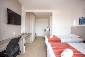 a hotel room with two beds and a flat screen tv at Apartment 905 - Prime location in Macaé in Macaé