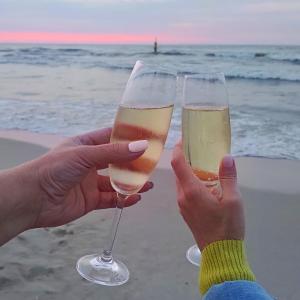 twee mensen met een glas champagne op het strand bij Apartamenty Amarel in Stegna