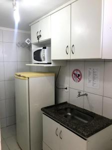 a small kitchen with a sink and a microwave at DiRoma resort Caldas Novas in Caldas Novas