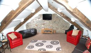a living room with two red chairs and a tv at Orchard Barn, Woodhayes in Honiton