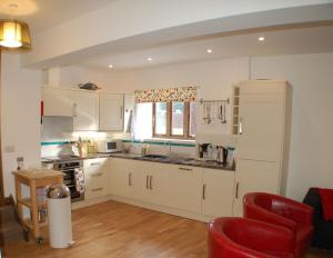 uma cozinha com armários brancos e uma cadeira vermelha em Orchard Barn, Woodhayes em Honiton