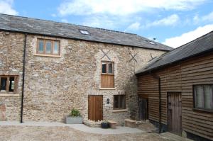 an old brick building with wooden doors and windows at Orchard Barn, Woodhayes in Honiton