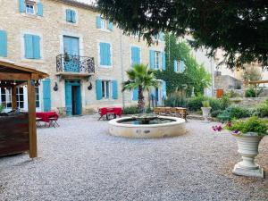 a courtyard with a fountain in front of a building at Aux Berges du Libre in Félines-Termenès