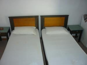 two twin beds in a room with two tables at Agios Antonios in Perissa