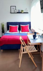 een slaapkamer met een bed met rode kussens en een tafel bij Apartamenty Amarel - Wilk Morski in Stegna