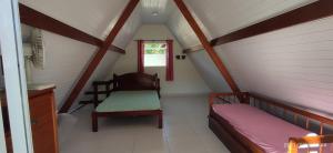 um pequeno quarto no sótão com uma cama e uma cadeira em Chale da Dalva em Ubatuba