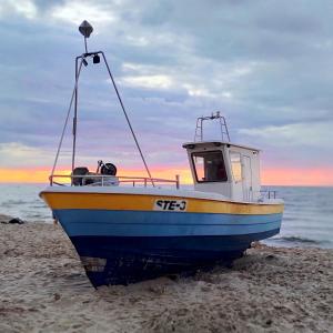 a blue and yellow boat sitting on the beach at Apartamenty Amarel - Wilk Morski in Stegna