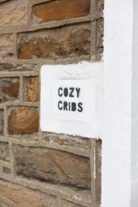 a sign on a brick wall with the words cozy girls at Cozy Cribs near Zipworld, Dare Valley Bike Park, Pen-y-fan & Four Waterfalls Walk in Aberdare