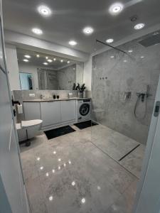 een badkamer met een douche, een wastafel en een toilet bij NADJEZIORNA LUX 3 in Ełk