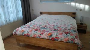 a bed with a floral comforter on it in a bedroom at B&B - Make a Wisch in Silvolde