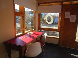 a red table and chairs in a room with windows at CasaEstudio in El Chalten