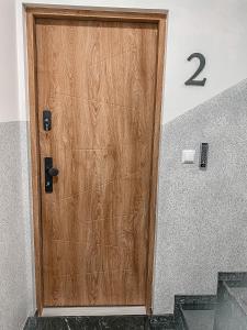 a wooden door with the number on the wall at NADJEZIORNA LUX 2 in Ełk