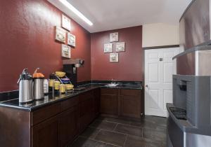 a large kitchen with red walls and a counter top at Red Roof Inn Neptune - Jersey Shore in Neptune City