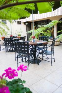 una mesa al aire libre y sillas con flores rosas en el patio en Hotel Casino Plaza, en Guadalajara