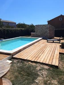 a swimming pool with a wooden deck and a bench at Villa confortable avec piscine privée à Saint-Saturnin-lès-Apt in Croagnes