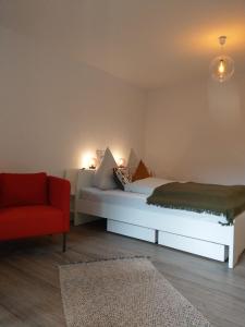 ein Schlafzimmer mit einem weißen Bett und einem roten Stuhl in der Unterkunft Claar Ferienwohnung Lindau Bodensee in Lindau