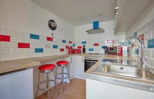 a kitchen with a sink and two red stools at Violets Wonderland Cottage in Llandudno